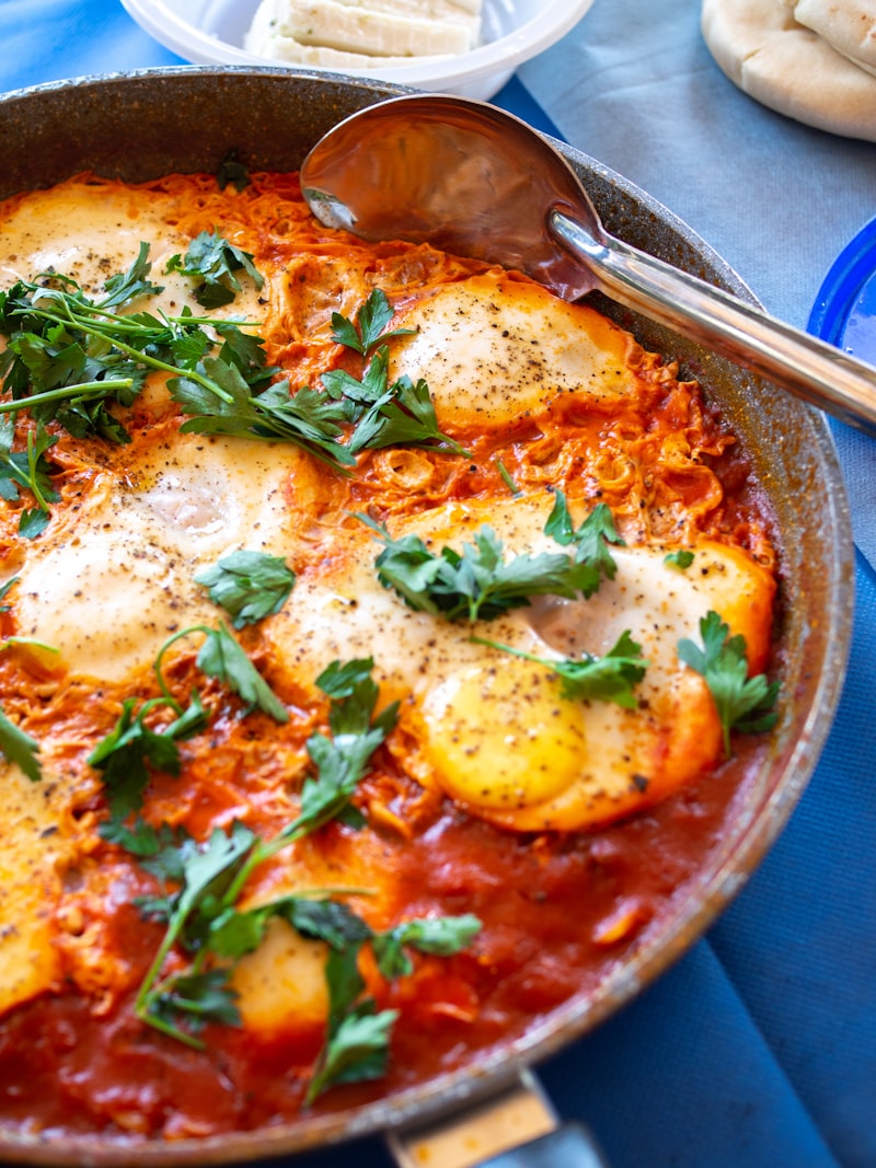 Shakshuka platter — poached eggs in a spiced tomato and pepper sauce, served with pita, chopped salad and hummus