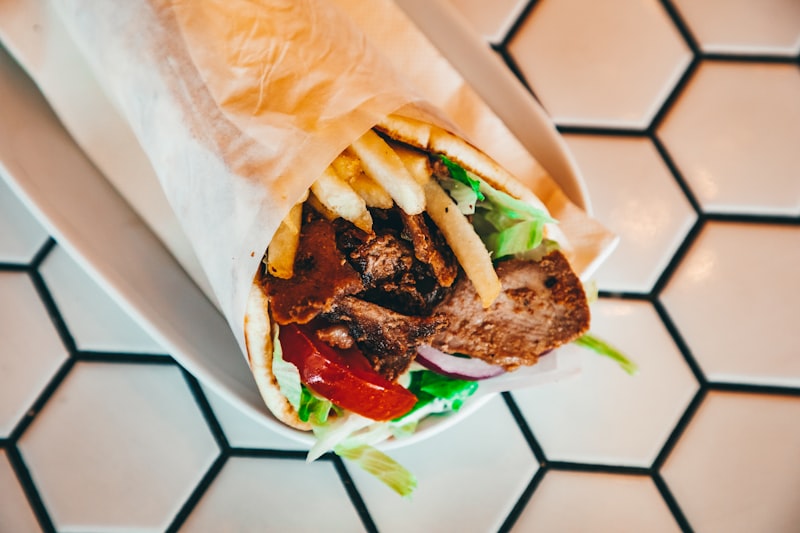 Shawarma-spiced tofu with fried onions wrapped in a pita with hummus, tahini and chopped salad