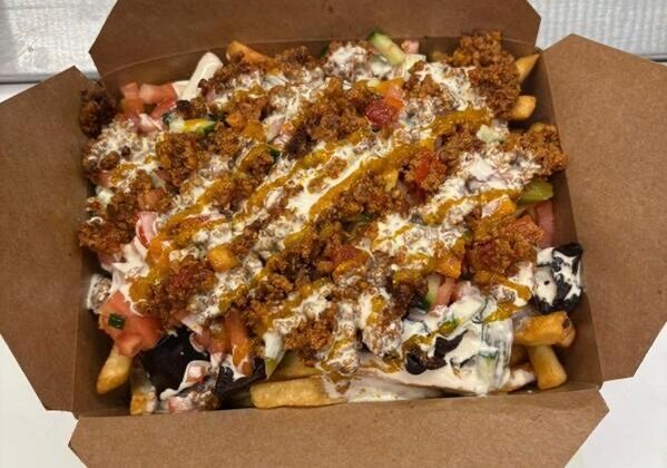 Loaded fries topped with vegan seasoned beef, tahini, chopped salad, pickles and eggplant