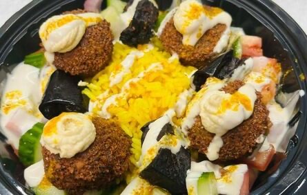 Rice bowl — yellow rice and fried onion with hummus, tahini, pickles, chopped salad and eggplant